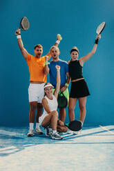 Athletes celebrate as a team, shouting and raising their rackets after winning a padel match. Padel players competing together in a sports championships game. This photo has intentional use of 35mm film grain. - JLPPF02377