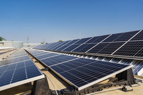 Auf einem Dach installierte Solarmodule, die saubere Energie aus dem strahlend blauen Himmel über uns nutzen. - DIGF20247