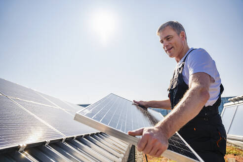 A skilled worker fitting solar panels onto the rooftop of a corporate establishment - DIGF20250