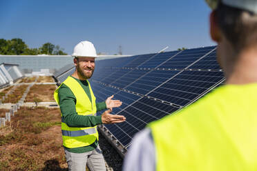Two technicians discussing the solar panel installation on the rooftop of a company building - DIGF20273