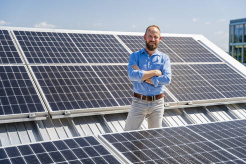 A self-assured businessman stands confidently amidst a field of solar panels - DIGF20355