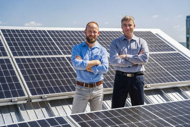 Zwei Geschäftsleute strahlen Zuversicht aus, als sie zwischen Reihen von Solarmodulen stehen und bereit sind, die Kraft der Sonne zu nutzen. - DIGF20356