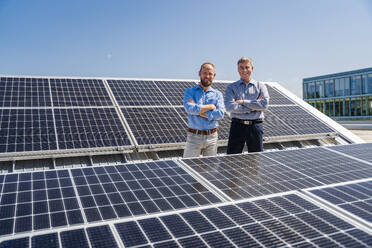 Two businessmen exude confidence as they stand among rows of solar panels, showcasing their commitment to renewable energy. - DIGF20357