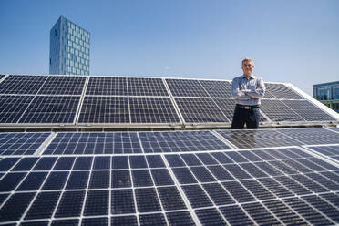 A self-assured male entrepreneur standing proudly in the midst of a field of solar panels - DIGF20359