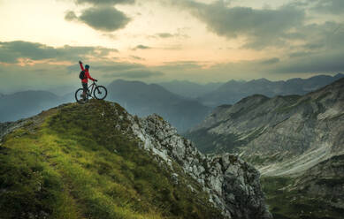 Aktiver Mann mit Fahrrad auf einem Berg bei Sonnenuntergang - HHF05895