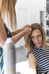 Hairdresser styling woman's hair at salon - PBTF00132