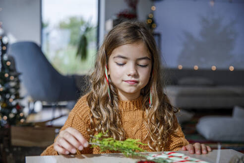 Girl holding Christmas decorations at table - IKF01144