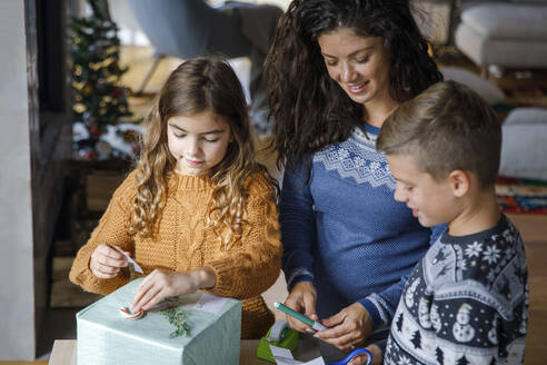 Familie dekoriert Geschenkbox für Weihnachtsfeier zu Hause - IKF01154