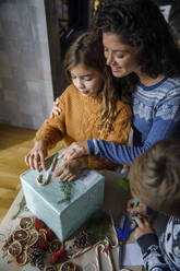 Familie dekoriert Weihnachtsgeschenk zu Hause - IKF01156