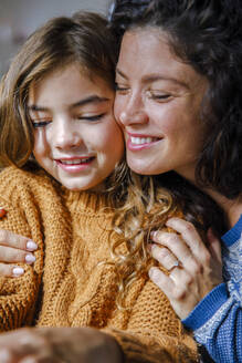 Lächelnde Mutter, die ihre Tochter zu Hause umarmt - IKF01158