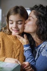 Mutter küsst lächelnde Tochter zu Hause - IKF01159