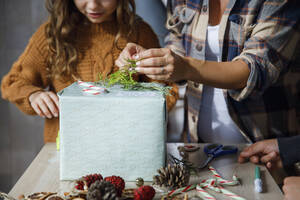 Familie dekoriert Weihnachtsgeschenkbox auf dem Tisch zu Hause - IKF01168