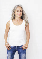 Glückliche Frau in Jeans vor weißem Hintergrund - JBYF00241
