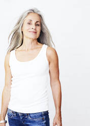 Mature woman standing against white background - JBYF00244