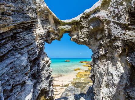 Blue and turquoise Sargasso Sea, glimpsed through an arch in the island's distinctive rocks, Bermuda, Atlantic, North America - RHPLF26872