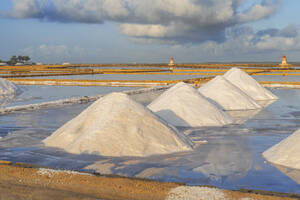 Piles of salts among salt flats with windmills in the background at sunset, Saline Ettore e Infersa, Marsala, province of Trapani, Sicily, Italy, Mediterranean, Europe - RHPLF26906