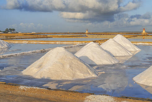 Piles of salts among salt flats with windmills in the background at sunset, Saline Ettore e Infersa, Marsala, province of Trapani, Sicily, Italy, Mediterranean, Europe - RHPLF26906