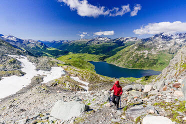 Hiker walking on mountain ridge above the blue lake Montespluga, Madesimo, Valle Spluga, Valtellina, Lombardy, Italy, Europe - RHPLF27288