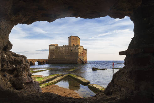 Tourist bewundert die Burg von Torre Astura durch eine Höhle im Boden gesehen, Provinz Rom, Tyrrhenisches Meer, Latium (Lazio), Italien, Europa - RHPLF27292