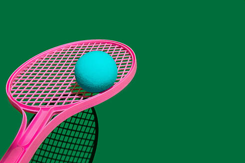 Creative design of blue ball on pink tennis racket against green sports ground with shadow in daylight - ADSF46673