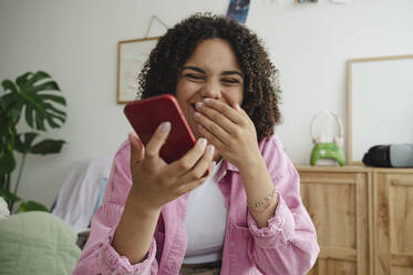 Fröhliches Mädchen benutzt Smartphone zu Hause - ALKF00542