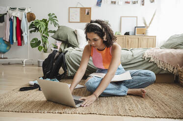 Teenage girl using laptop and doing homework at home - ALKF00558