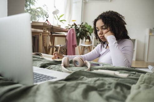 Curly haired girl doing homework at home - ALKF00571