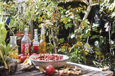 Früchte und verschiedene Ölflaschen auf dem Gartentisch - HHF05913
