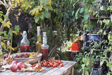 Früchte und verschiedene Ölflaschen auf dem Gartentisch - HHF05916