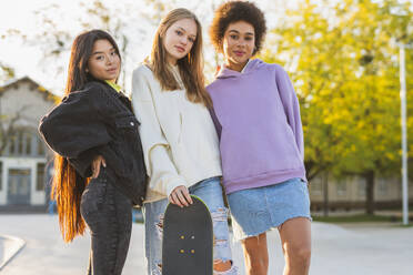 Multicultural group of young friends bonding outdoors and having fun - Stylish cool teens gathering at urban skate park - DMDF02922