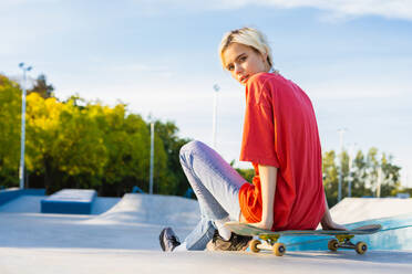 Stylish cool teen female skateboarder at skate park - DMDF02928