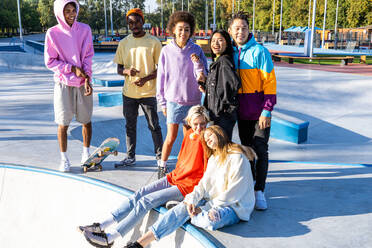 Multikulturelle Gruppe junger Freunde, die sich im Freien treffen und Spaß haben - Stylische, coole Teenager treffen sich im städtischen Skatepark - DMDF02942