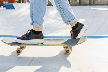 Stylish cool teen female skateboarder at skate park, close-up on shoes - DMDF02948