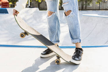 Stylish cool teen female skateboarder at skate park, close-up on shoes - DMDF02949