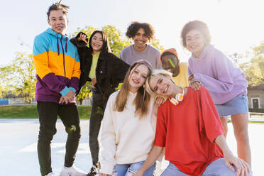 Multicultural group of young friends bonding outdoors and having fun - Stylish cool teens gathering at urban skate park - DMDF02955