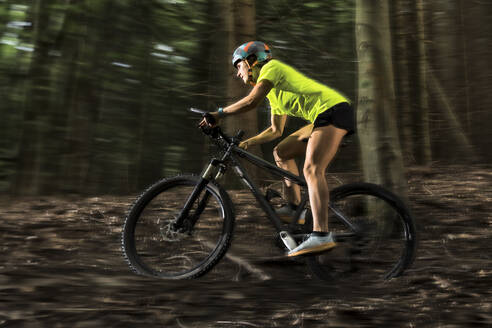 Adventurous athlete riding mountain bike in forest - STSF03755