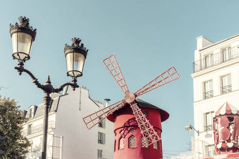 Frankreich, Ile-de-France, Paris, Straßenlaterne vor der roten Windmühle des Kabaretts Moulin Rouge - TAMF03923