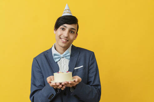 Smiling man holding 18th birthday cake in studio - OSF02027