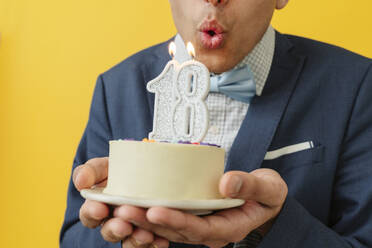 Mann bläst Kerze zum 18. Geburtstag auf Kuchen - OSF02029