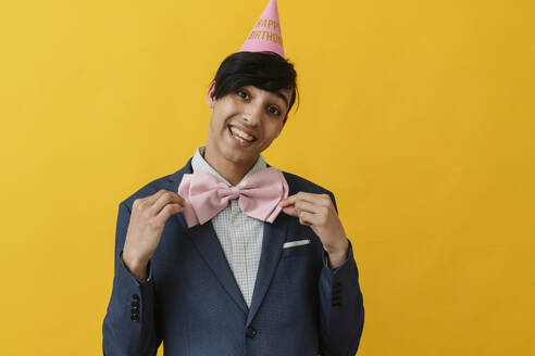 Cheerful man wearing bow tie and party hat on birthday - OSF02032