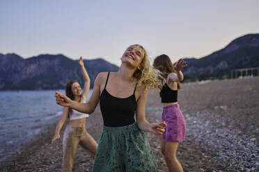 Sorglose Freunde tanzen am Strand im Urlaub - ANNF00395