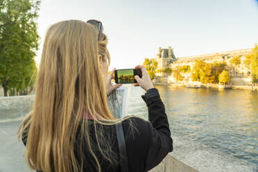Blonde Touristin fotografiert die Seine mit ihrem Smartphone - TAMF03938