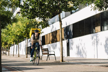 Delivery person with bag riding on bicycle - DAMF01214