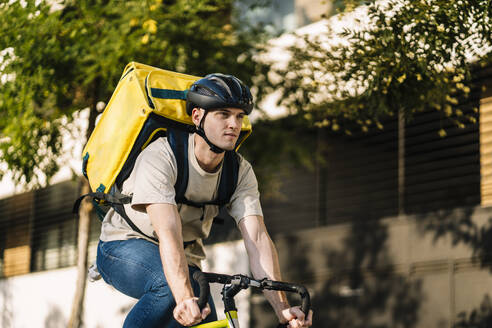 Delivery person with bag riding bicycle - DAMF01215