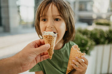 Father's hand feeding ice cream to son - ANAF01980