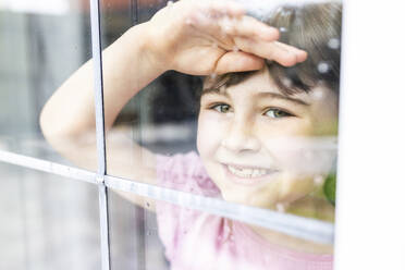 Smiling girl looking through window - WPEF07562