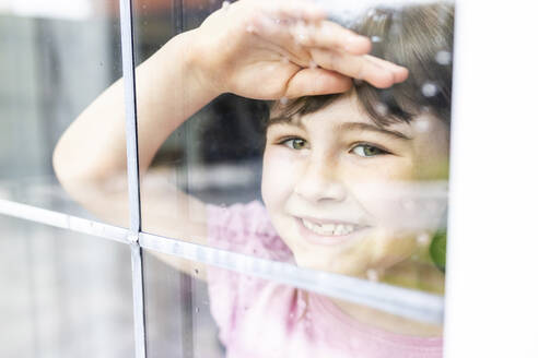 Lächelndes Mädchen schaut durch das Fenster - WPEF07562