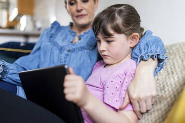 Mädchen benutzt Tablet-PC bei der Mutter im Wohnzimmer - WPEF07564