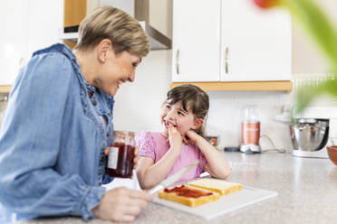 Happy mother and daughter preparing breakfast in kitchen - WPEF07575