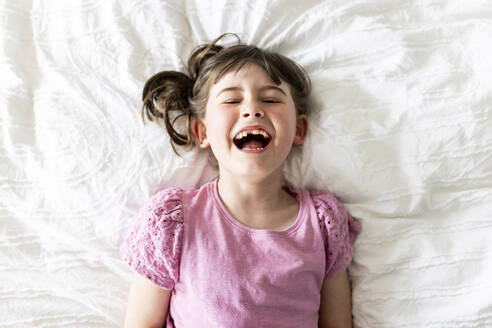 Nettes Mädchen lachend und liegend auf dem Bett zu Hause - WPEF07594
